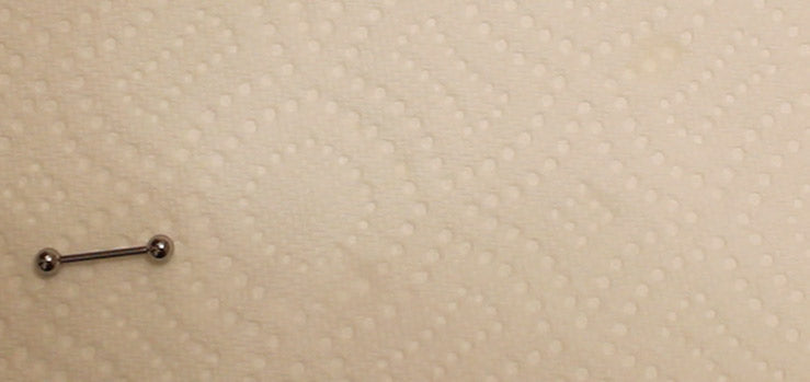 Silver-tone straight barbell lying on a textured white paper towel