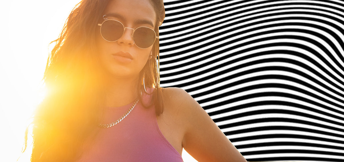 Woman in round sunglasses with a nostril hoop, an eyebrow ring and large hoop earrings