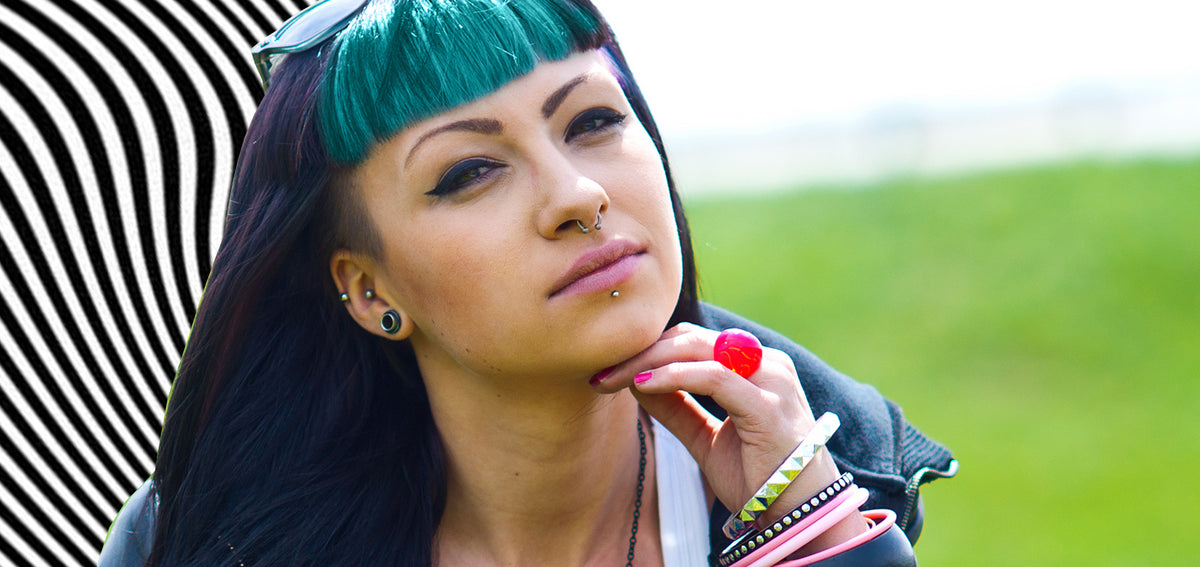 Woman with teal bangs wearing a septum ring, a labret stud, small ear studs and a black tunnel in her stretched lobe