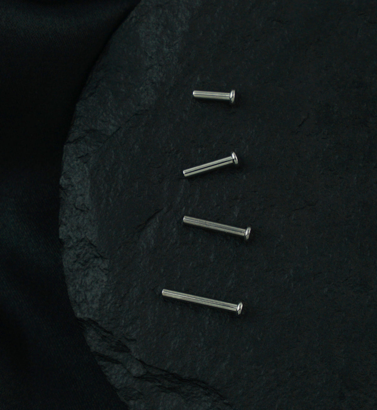 Titanium Threadless Labret, four posts lined up on dark stone
