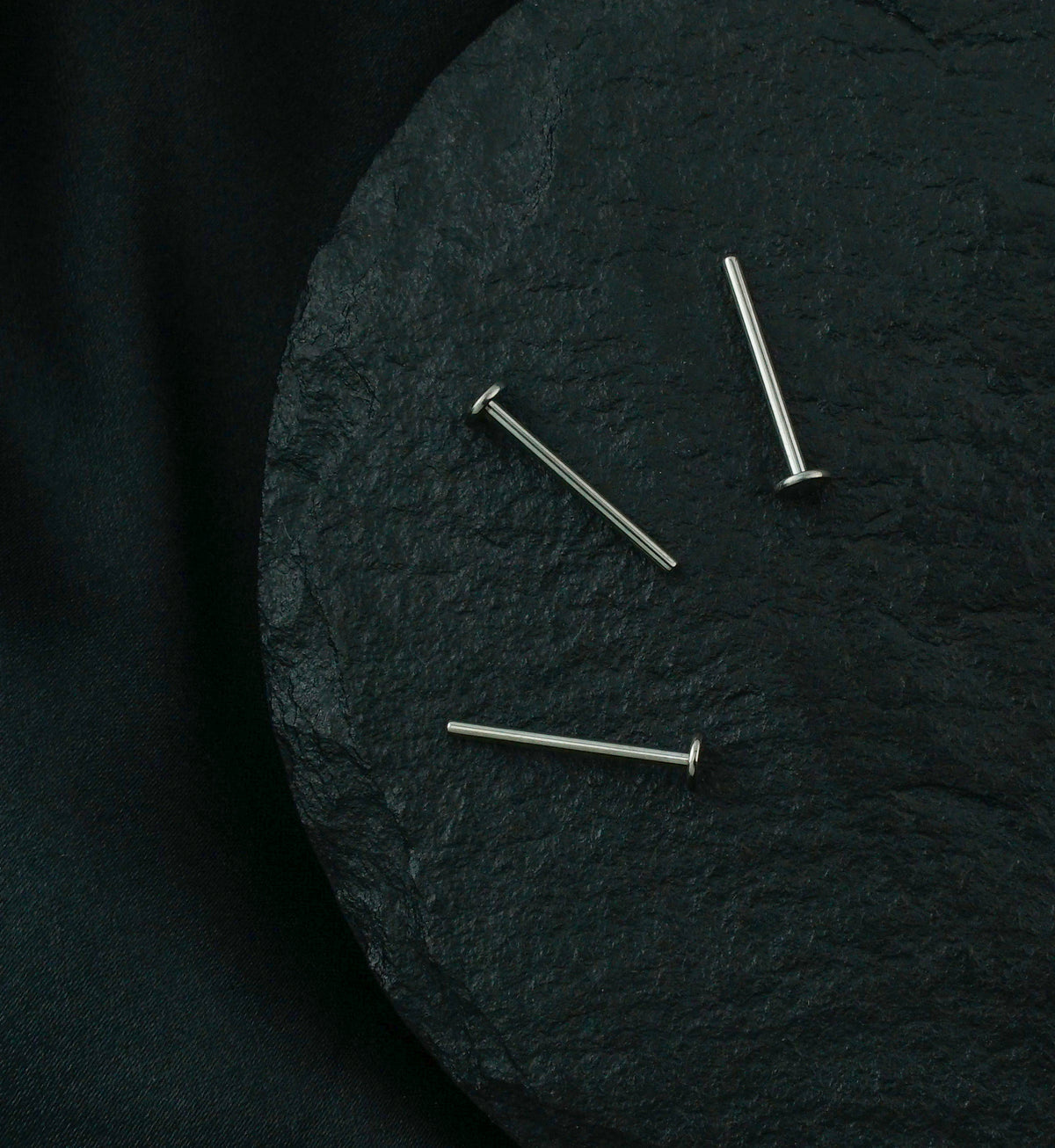 Titanium Threadless Labret, three posts scattered on dark stone